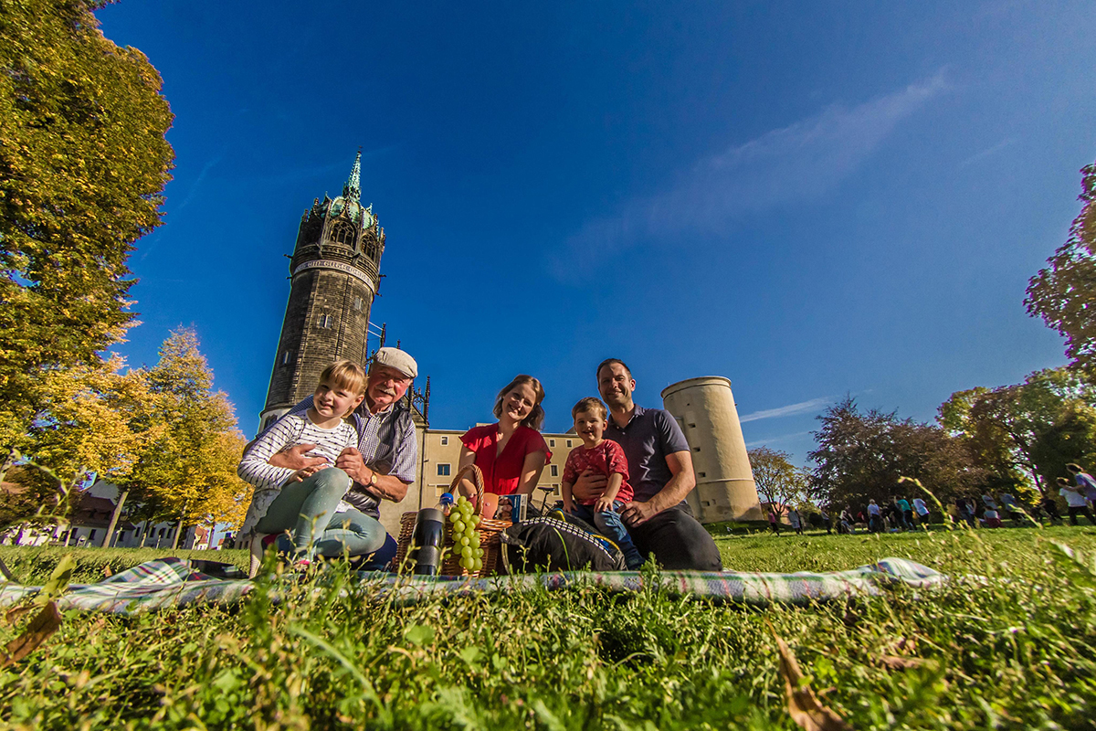 Familie macht ein Picknick vor der Schloßkirche in Wittenberg