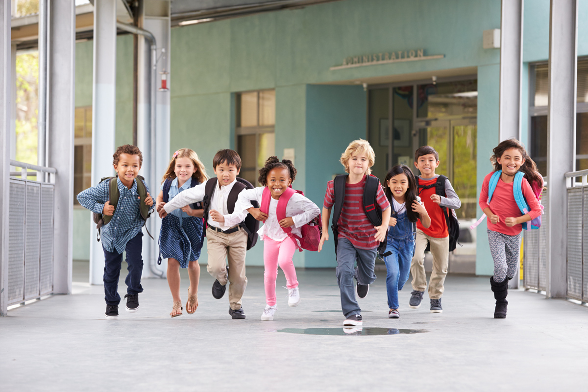 Gruppe von Grundschulkindern, die in einem Schulkorridor laufen