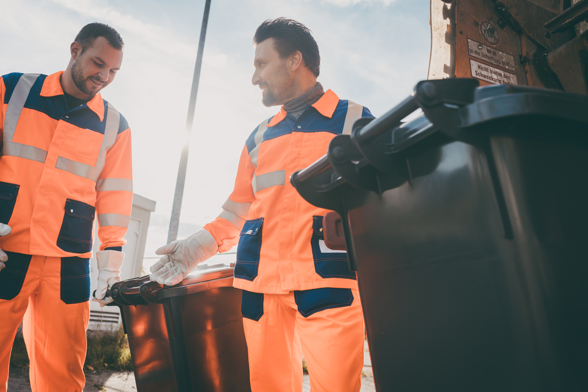 Müllentsorgungsmänner, die für ein öffentliches Versorgungsunternehmen arbeiten und Müllcontainer leeren